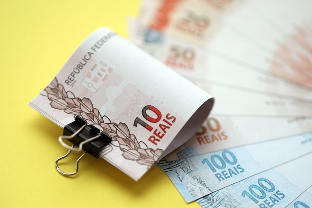 Close Up Of Brazilian Reais Money Bills In Big Amount On Yellow. Pile Of Brazil Real Currency - Contabilidade em Brasília - DF | Expert Easy Contabilidade