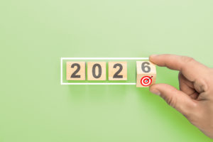 Hand Completing 2026 New Year Business Goals. Man Putting Last Wooden Block With Target Icon In White Frame Concept - Contabilidade em Brasília - DF | Expert Easy Contabilidade