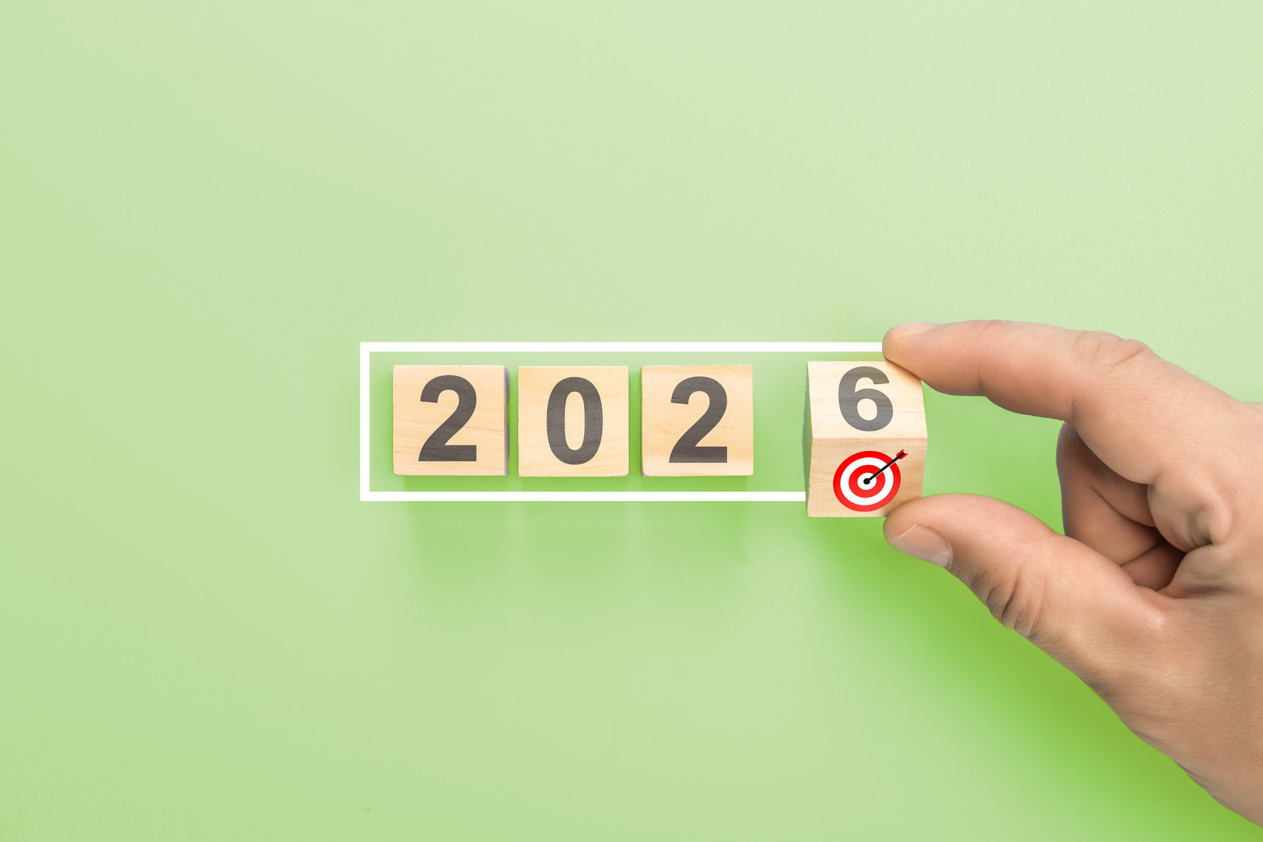 Hand Completing 2026 New Year Business Goals. Man Putting Last Wooden Block With Target Icon In White Frame Concept - Contabilidade em Brasília - DF | Expert Easy Contabilidade